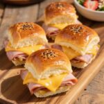 Freshly baked ham and cheese sliders with golden tops and melted cheese